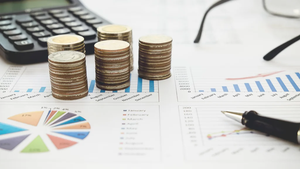 Graphiques financiers et piles de pièces illustrant l'analyse des revenus générés par un apporteur d'affaires en banque